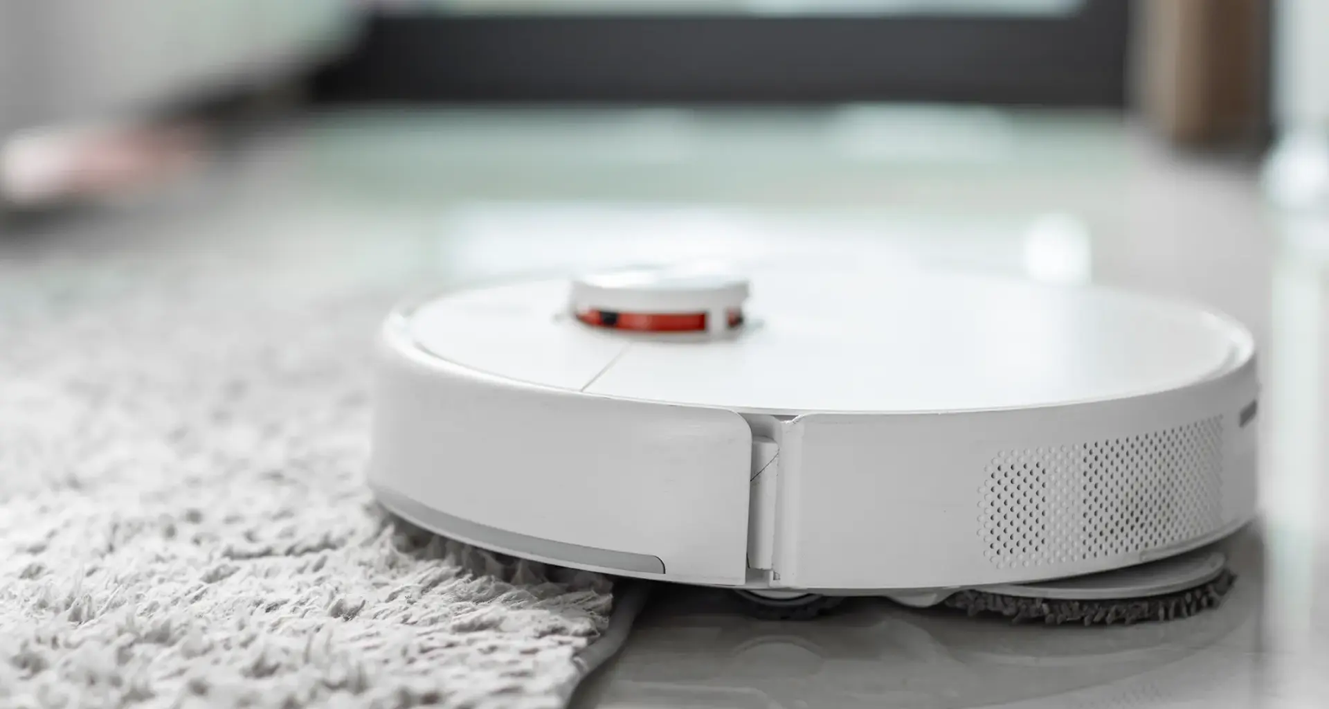 Imagen de un robot aspirador pasando encima de una alfombra
