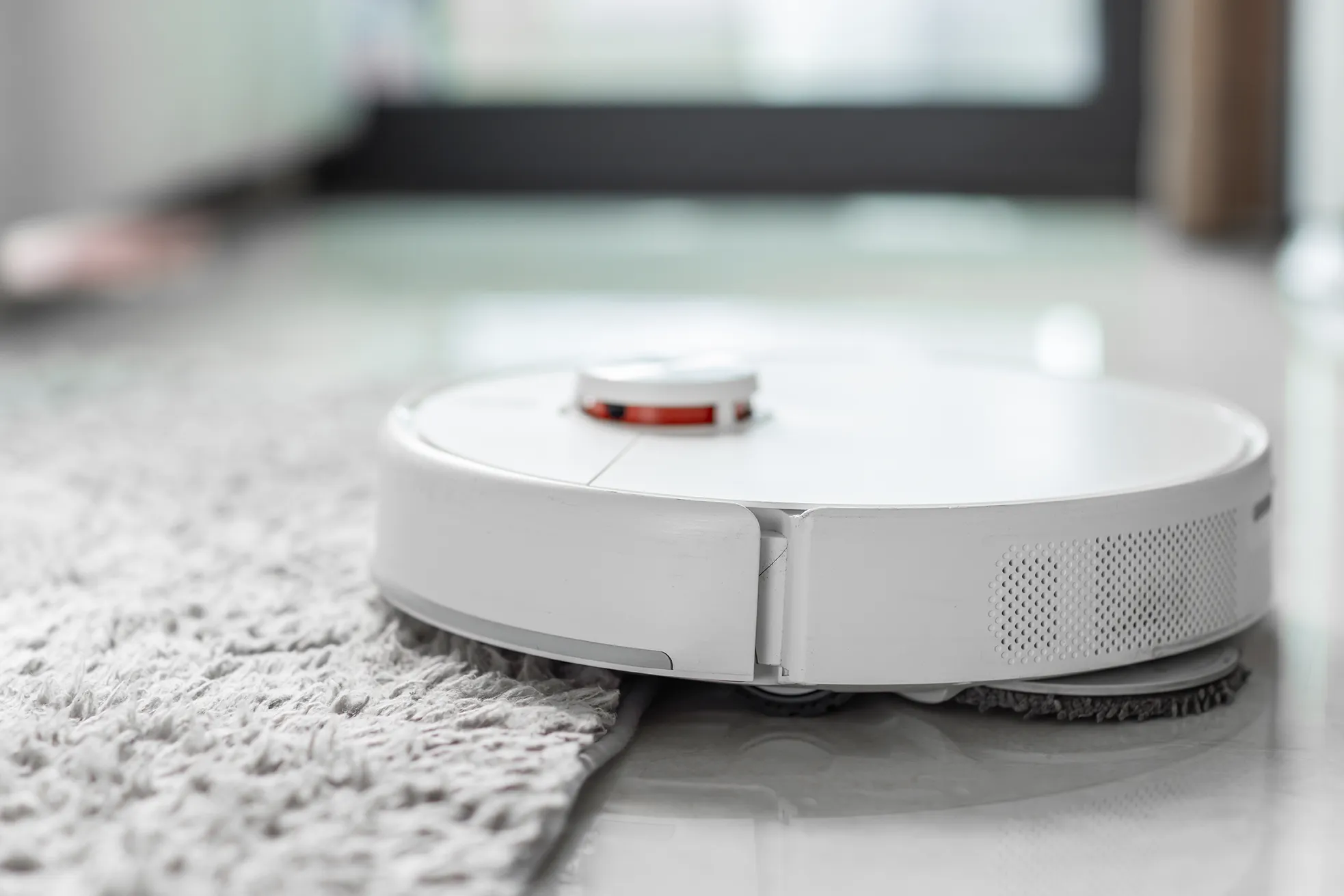 Imagen de un robot aspirador pasando encima de una alfombra